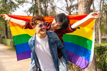 Joyful multi-ethnic gay couple waving lgbt flag piggybacking