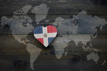wooden heart with national flag of dominican republic near world map on the wooden background.