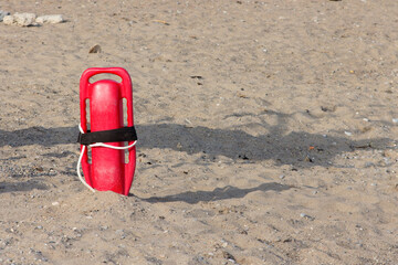 A red lifeguard's rescue float stuck in the sand on a beach