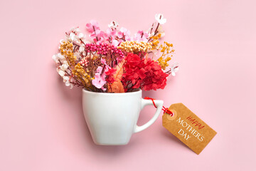 Happy Mother's Day. White cup of coffee with various flowers and brown sale tag with the text Happy Mothers day