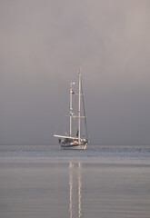 Sailboat in the middle of the ocean stopped, morning and misty environment