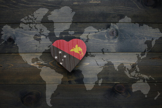 wooden heart with national flag of Papua New Guinea near world map on the wooden background. - Powered by Adobe