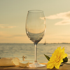 an empty wine glass on a table in a boat looking out at the water at sunset
