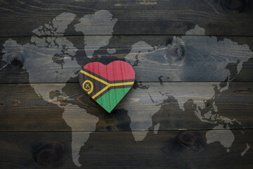 wooden heart with national flag of Vanuatu near world map on the wooden background.