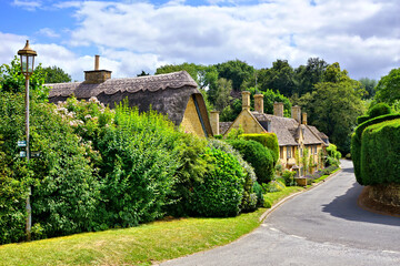 Picturesque street in a Cotswolds village with thatched roof house, Gloucestershire, England