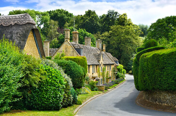Beautiful street in a Cotswolds village with thatched roof house, Gloucestershire, England