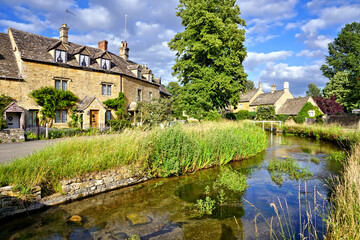 Fototapeta na wymiar Beautiful Cotswolds village of Lower Slaughter with river under blue skies, Gloucestershire, England