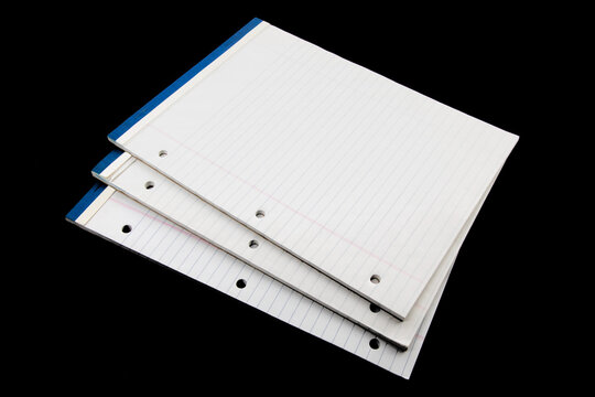 pads of white three hole punched note paper isolated on black