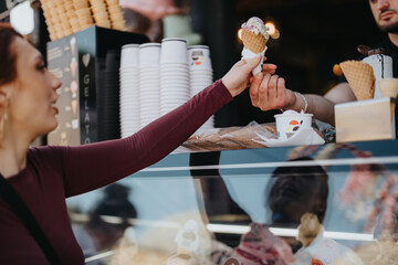A smiling young woman gets a delicious ice cream cone from a male vendor, signifying a sweet treat...