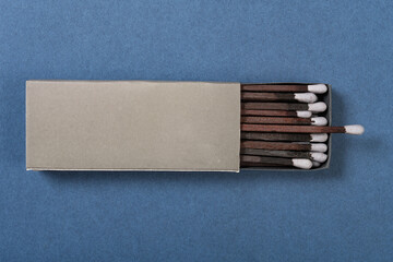 top view grey color matchbox and grey match sticks on a blue background