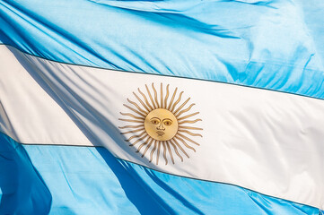 Full frame closeup photo of the Argentine flag, blue and white, with the yellow sun in the center,...