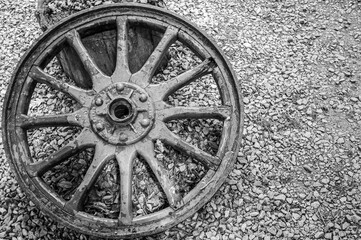 Black and white image of an old cart wheel on a stone background