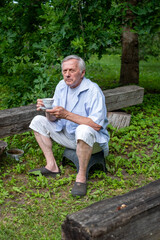 Obraz premium Contemplative elderly gentleman enjoying a quiet tea break in a verdant garden setting a moment of bucolic tranquility, and peaceful retirement.
