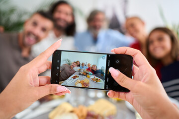 POV smart phone hold by unrecognizable woman taking photo of reunion Caucasian family in...