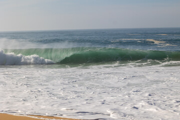 waves hit the sandy beach in fine weather with blue skies