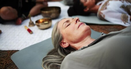 Woman, tibetan bowls or meditation at wellness, retreat or eyes closed as mindful, spiritual or practice. Healer, people or breath by lying in nature, sound or zen of esoteric indigenous medicine