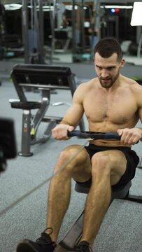 Shirtless athlete training rowing machine exercise intense endurance workout, slow motion