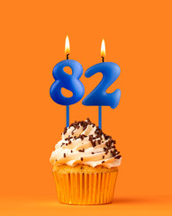 Blue candle number 82 - Birthday cupcake on orange background