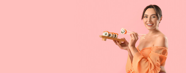 Happy young woman with set of tasty Philadelphia sushi rolls on pink background