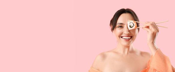 Happy young woman with tasty Philadelphia sushi roll on pink background