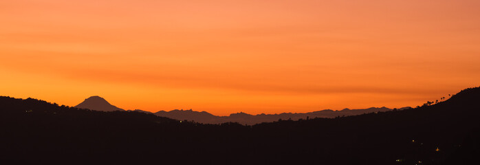 Mountain range silhouette in landscape of yellow sunset 