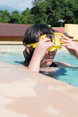 Girl taking googles in swimming pool in hot sunny day