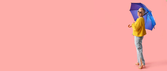 Naklejka premium Beautiful mature woman with umbrella on pink background