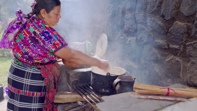 The grandmother adds portions of chicken to the pot where chicken soup is prepared, the granddaughter takes photos and videos to share the experience on social networks.