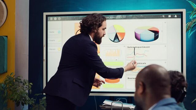 Financial analyst briefing his team about new company objectives, making budget and sales presentation with interactive board. Specialist addressing resource allocation and project planning. Camera A.