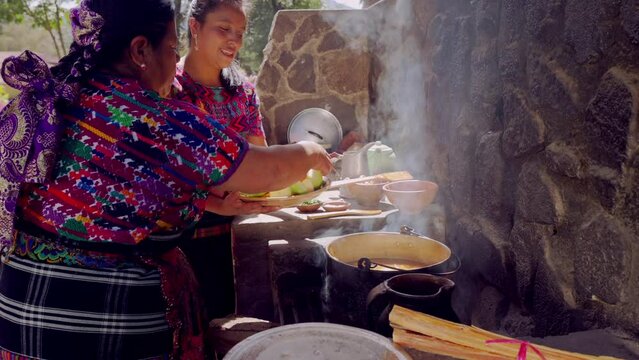 A Latina cook from the Mayan ethnic group, she adds vegetables to a chicken broth that she prepares for a family's lunch.