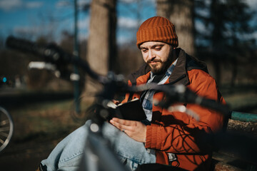 Young man enjoys a peaceful moment in the park, using his smart phone with his bicycle beside him.