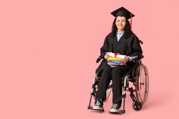 Beautiful female graduate student in wheelchair with graduation cap, diploma and books on pink...