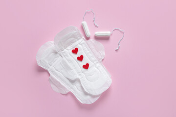 Menstrual pads with red hearts and tampons on pink background © Pixel-Shot