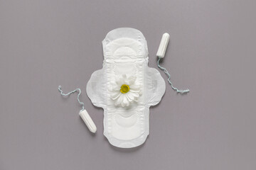 Menstrual pad with tampons and chrysanthemum flower on grey background