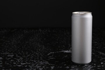Energy drink in can on black textured table, space for text