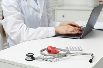 Endocrinologist working at table, focus on stethoscope and model of thyroid gland