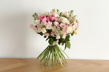 Beautiful bouquet of fresh flowers on wooden table near white wall - obrazy, fototapety, plakaty