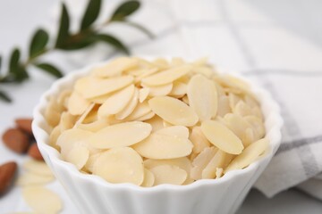 Fresh almond flakes in bowl on blurred background, closeup
