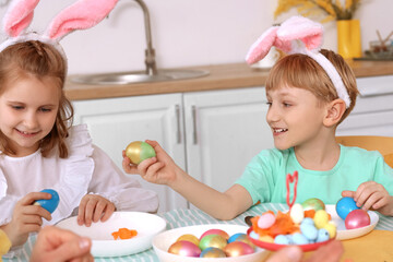 Little children with Easter eggs having dinner in kitchen