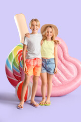 Cute little kids with inflatable mattresses and beach ball on lilac background - obrazy, fototapety, plakaty