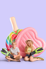 Cute little kids with inflatable mattresses and flippers on lilac background