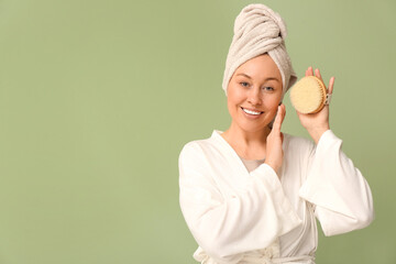 Beautiful young woman with body massage brush on green background