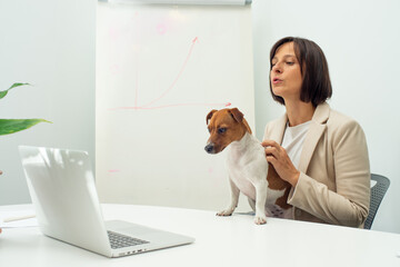 smart dog and businesswoman at table in office with laptop