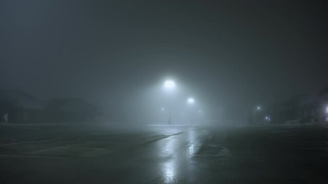 Wide shot of Heavy fog in a empty parking lot out the street white street lights at night time