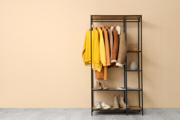 Rack with stylish female clothes, shoes and decor near color wall - Powered by Adobe