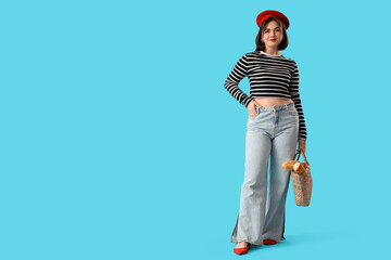 Portrait of fashionable young woman in beret with baguettes on blue background - obrazy, fototapety, plakaty
