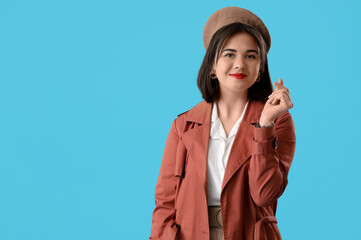 Portrait of fashionable young woman in beret on blue background