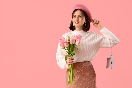 Portrait of fashionable young woman in beret with tulip flowers on pink background