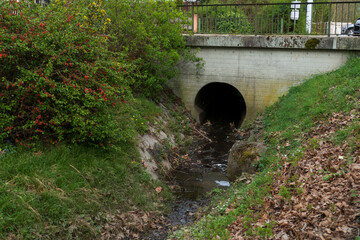 Abwasserkanal aus Beton führt Wasser in einen kleine Bach