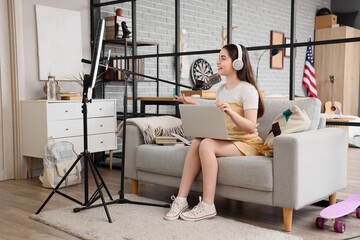 Female student with laptop and microphone streaming online at home